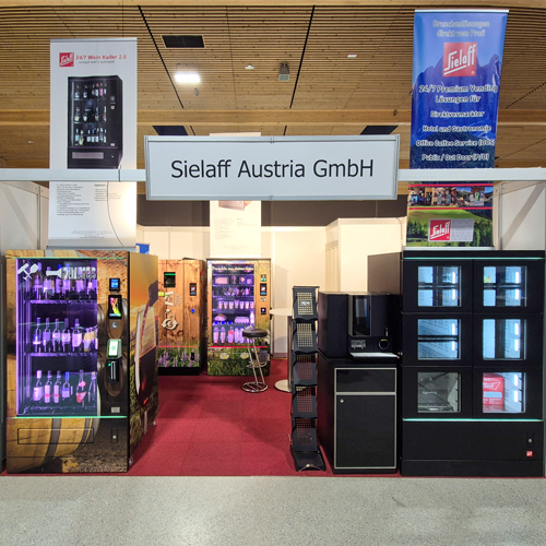 Trade show booth of Sielaff Austria GmbH featuring multiple beverage vending machines and information stands on red carpet in an exhibition hall.