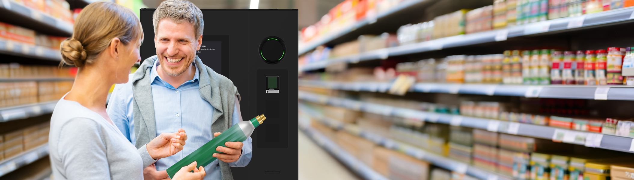 Ein Mann und eine Frau stehen vor dem SiLine SiLoop CO2 Tauschautomaten im Supermarkt, der Mann hält eine grüne CO2 Flasche in der Hand. Im Hintergrund sind Regale mit Waren zu sehen.